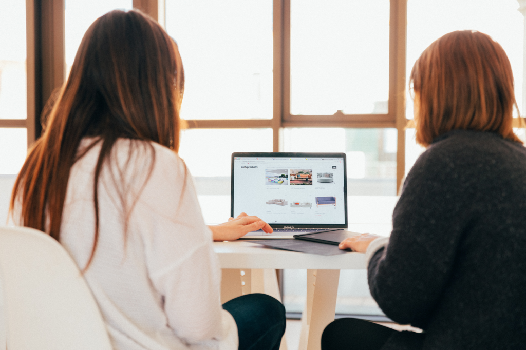 Deux femmes discutent devant un ordinateurs. Par Kobu Agency